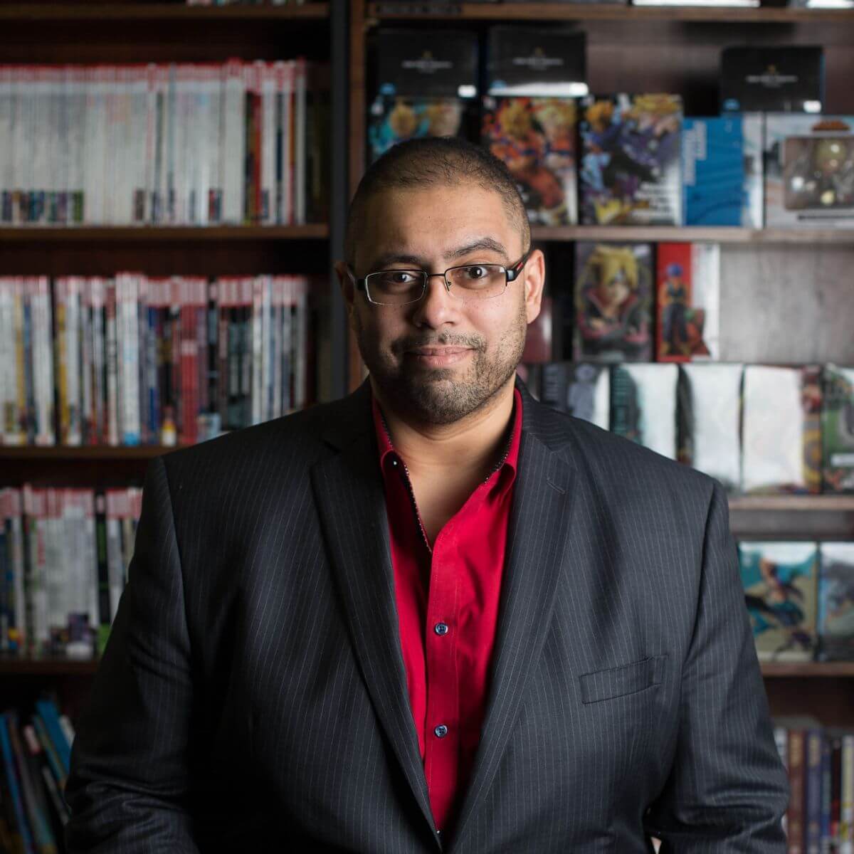 Professional headshot of Bilal Qizilbash, CEO of EK Foods, wearing a black suit and a red dress shirt.