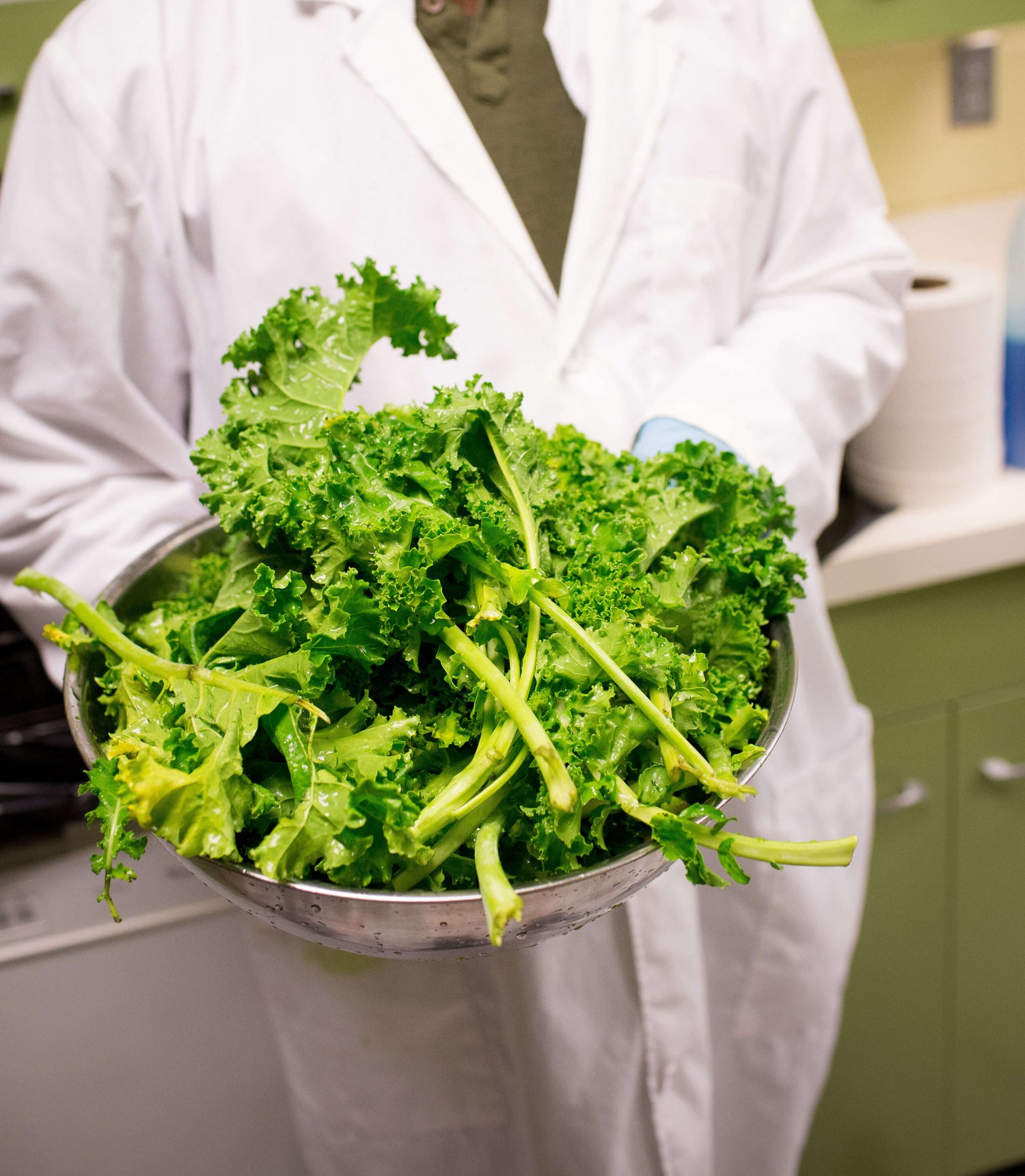 A man in a lab coat holding USDA certified kale, intended for making Bilal's EasyKale in the lab.